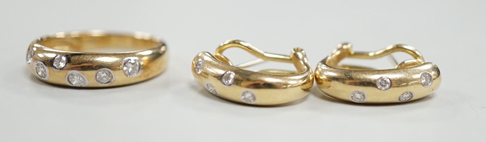 A modern 14k and gypsy set six stone diamond band, size N and a pair of matching earrings, gross weight 8.1 grams.